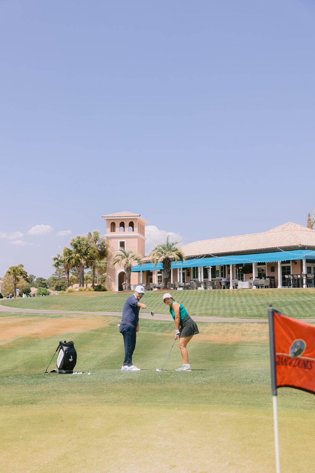 Billy Belair giving on-course instruction with the Grande Dunes clubhouse and Mediterranean tower in the background